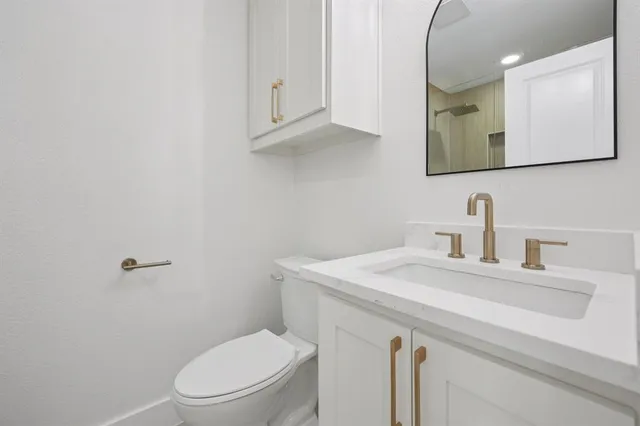 a bathroom with a toilet a sink a vanity and mirror