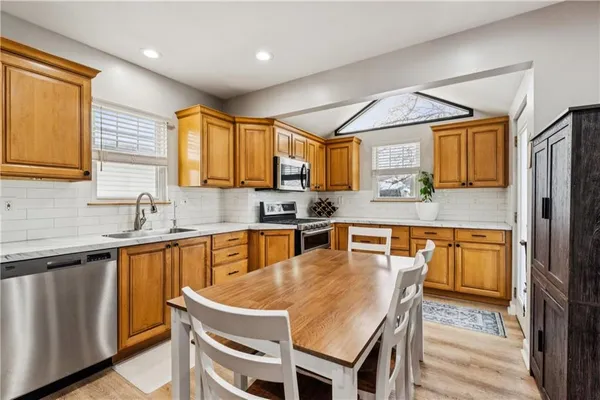 a kitchen with stainless steel appliances granite countertop a sink a stove a refrigerator cabinets and dining table