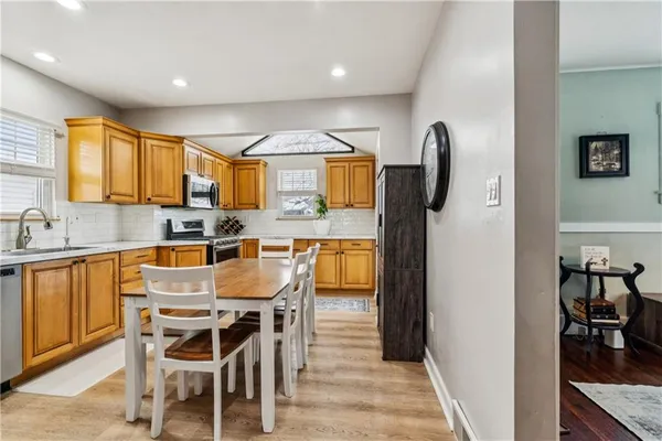 a dining room with stainless steel appliances kitchen island granite countertop a table chairs and a refrigerator