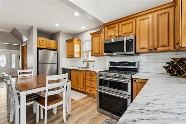 a kitchen with stainless steel appliances granite countertop a stove top oven a sink and a refrigerator