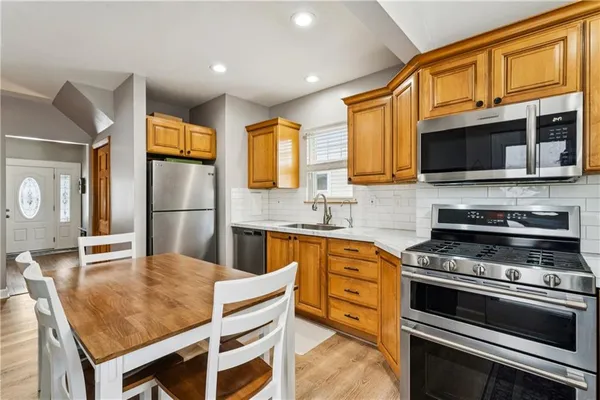 a kitchen with stainless steel appliances granite countertop a stove top oven a sink and a refrigerator