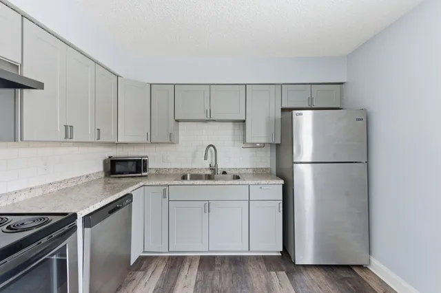 a kitchen with a sink a refrigerator and white cabinets