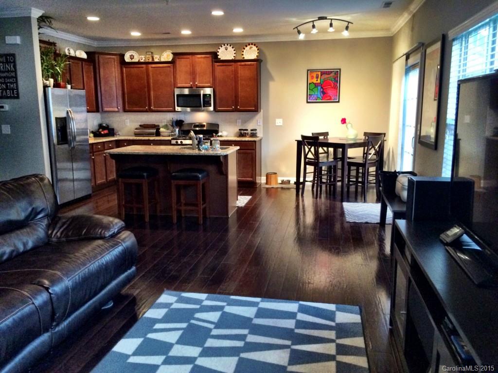 14713 Intermilan Way Charlotte, NC 28277 - Photo 3 of 16 a kitchen with stainless steel appliances granite countertop a stove top oven a sink a dining table and chairs with wooden floor