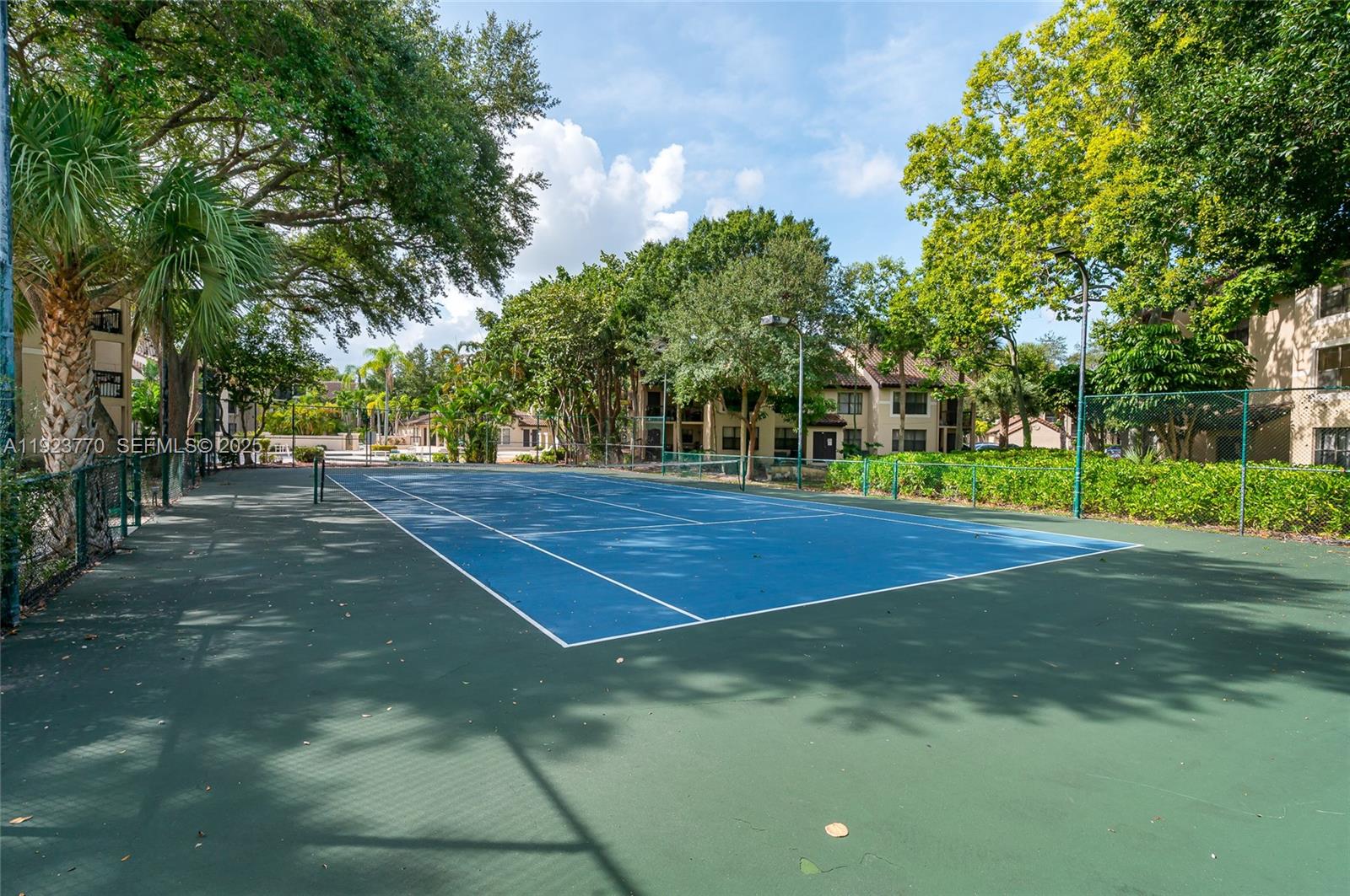 4201 West McNab Road, Unit 15 Pompano Beach, FL 33069 - Photo 3 of 18 a view of a tennis ground with large trees