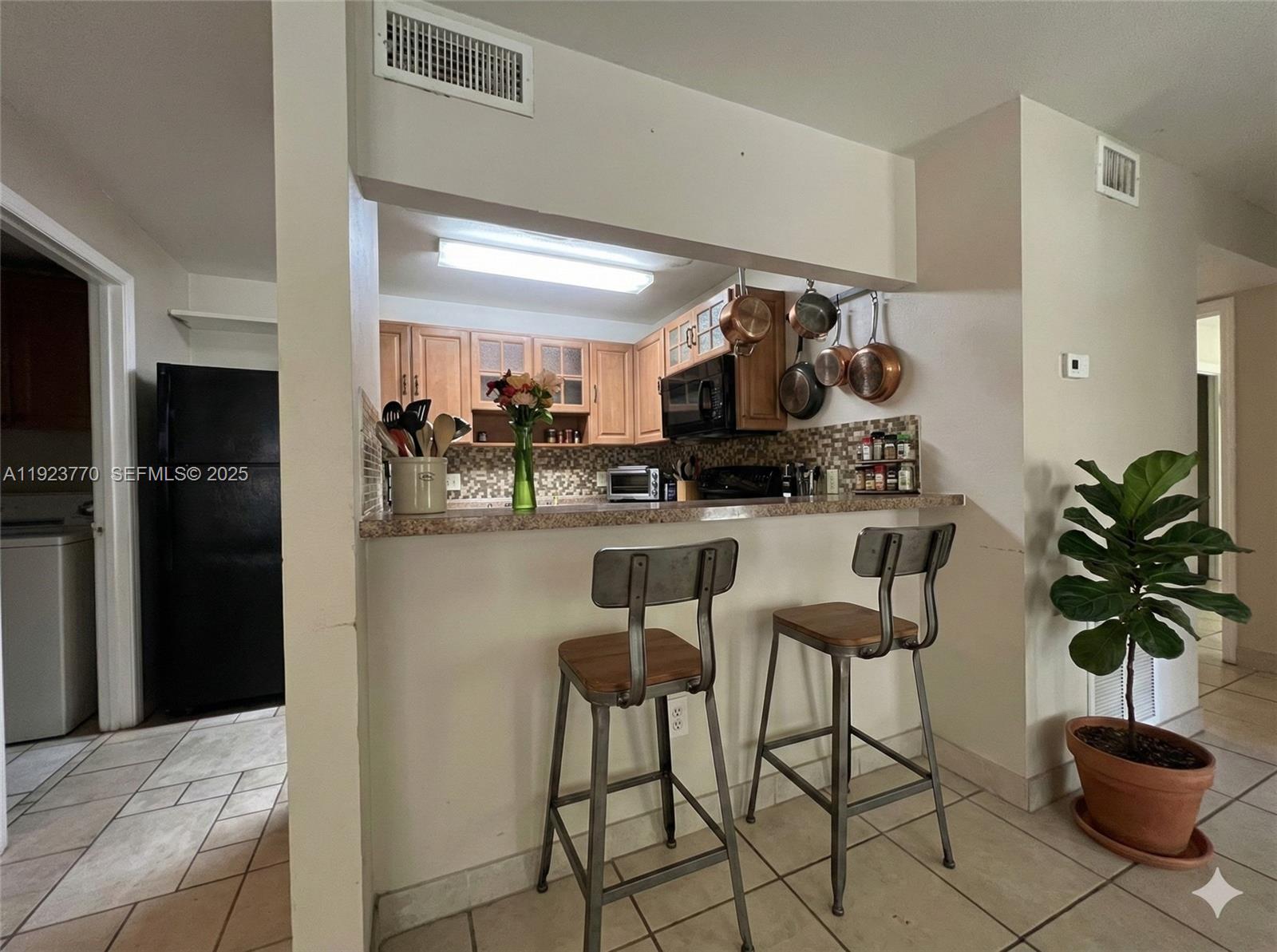 4201 West McNab Road, Unit 15 Pompano Beach, FL 33069 - Photo 8 of 18 a kitchen with stainless steel appliances kitchen island granite countertop a refrigerator a stove a microwave oven a sink with island and chairs