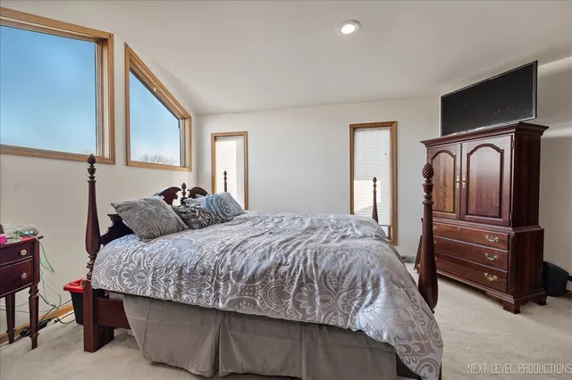 a bedroom with a bed and dresser with chair