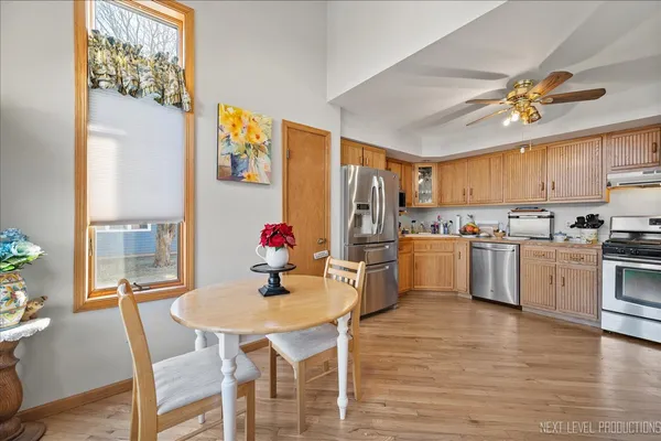 a kitchen with stainless steel appliances kitchen island granite countertop a refrigerator a stove top oven a dining table and chairs with wooden floor