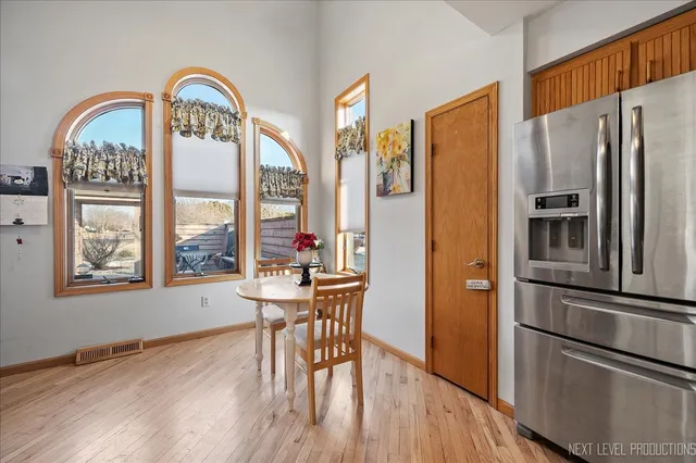 a kitchen with stainless steel appliances granite countertop a refrigerator a stove and a dining table with wooden floor