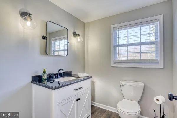 a bathroom with a toilet a sink a mirror and a window
