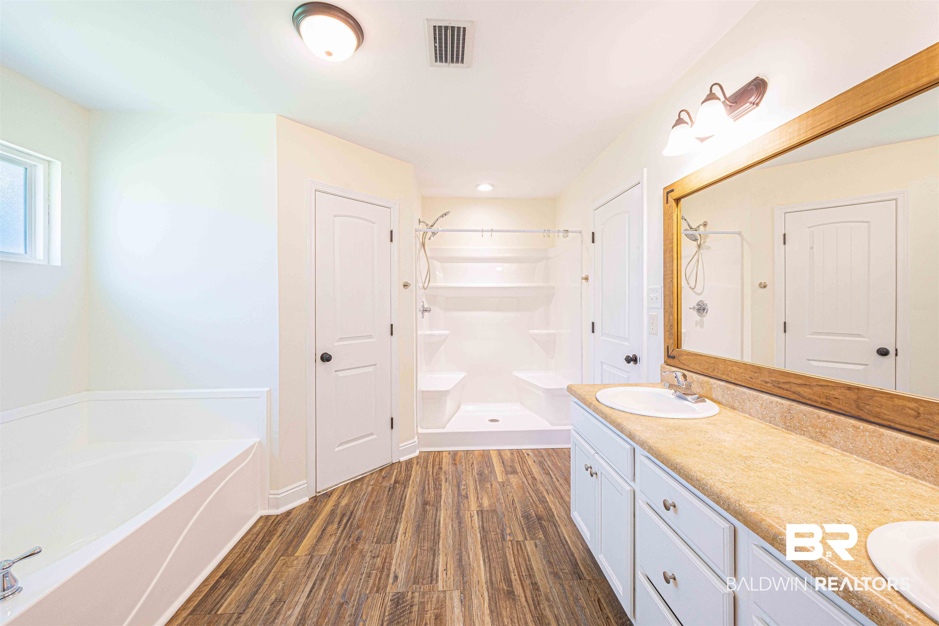 18675 Explorer Drive Loxley, AL 36551 - Photo 26 of 42 Bathroom with wood finished floors, a stall shower, a garden tub, and double vanity