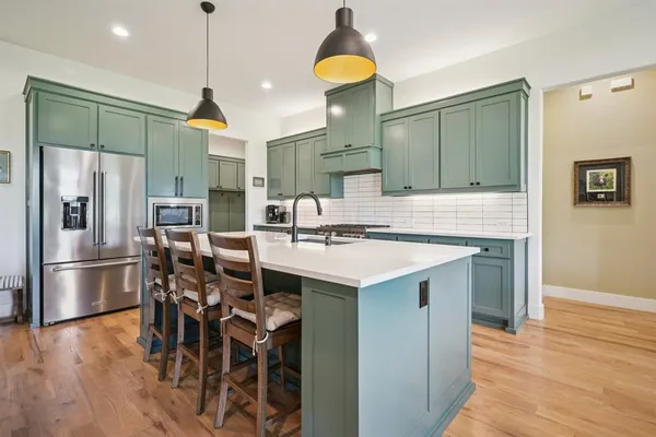 a kitchen with stainless steel appliances granite countertop a stove a sink dishwasher and a refrigerator with wooden floor