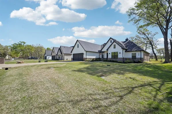 a view of a big house with a big yard and large trees