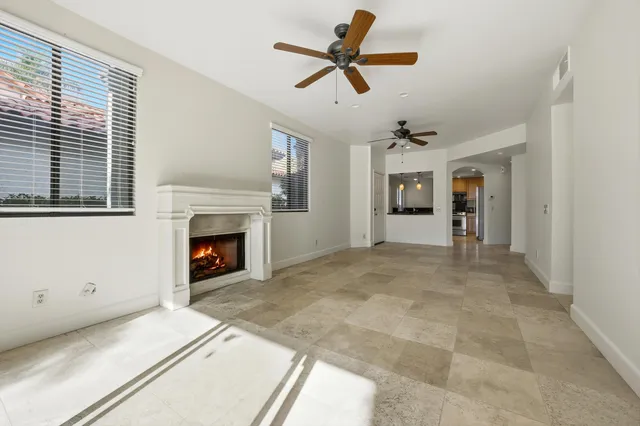 a view of a livingroom with a fireplace a ceiling fan and window