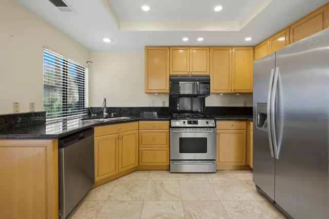 a kitchen with stainless steel appliances granite countertop a stove a sink and a refrigerator
