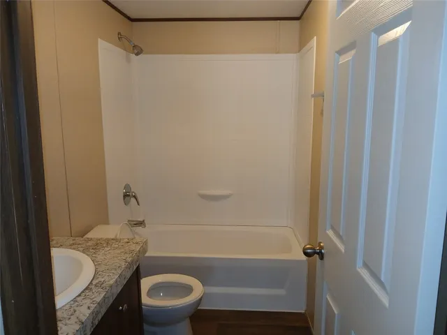 a bathroom with a granite countertop bathtub shower sink vanity and toilet