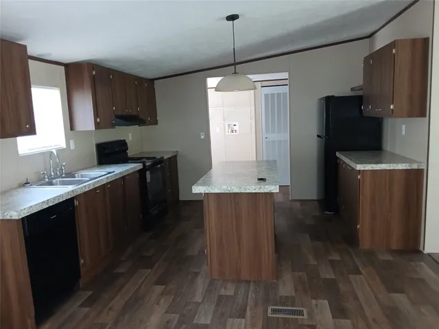 a kitchen with stainless steel appliances granite countertop a refrigerator a sink dishwasher a stove and white countertops with wooden floor