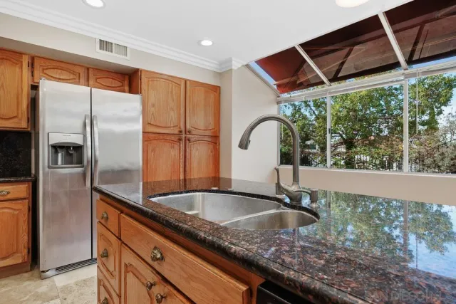 a kitchen with stainless steel appliances granite countertop a sink a refrigerator and window