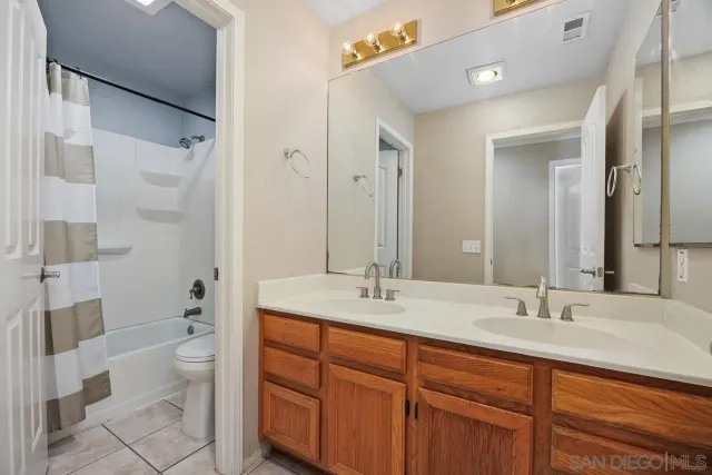 a bathroom with a double vanity sink toilet mirror and shower