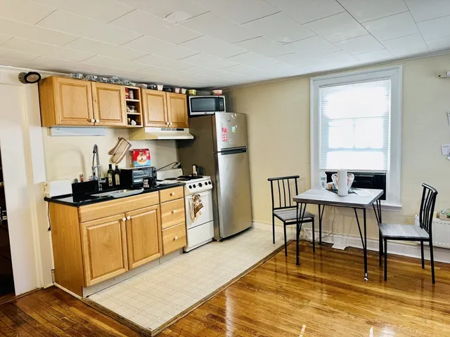 a kitchen with stainless steel appliances granite countertop a stove a sink dishwasher and a refrigerator with wooden floor