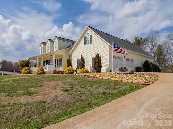 a view of a white house next to a yard with big trees