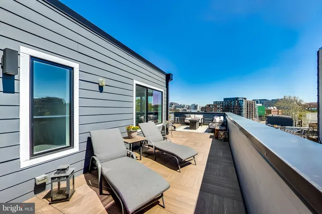 a view of a roof deck with table and chairs a barbeque with wooden floor and fence