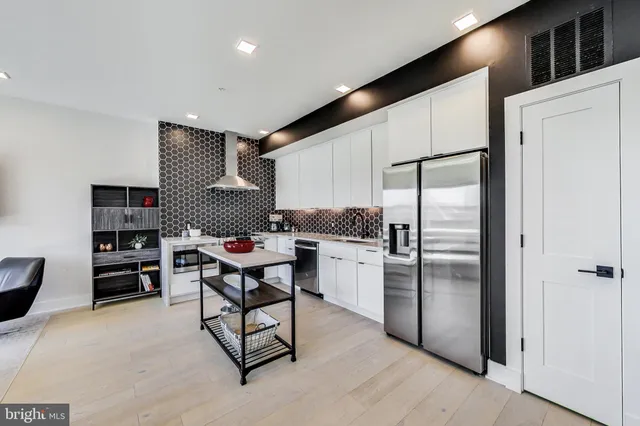 a kitchen with stainless steel appliances kitchen island granite countertop a refrigerator and a stove top oven