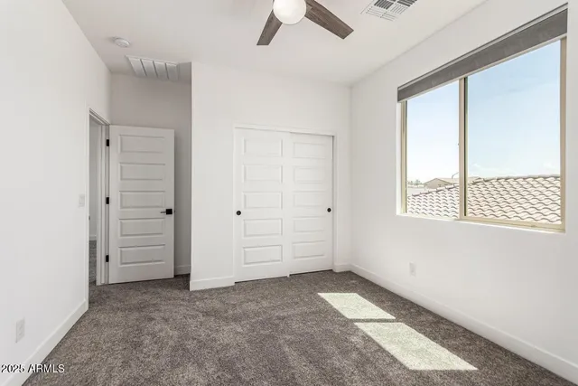 an empty room with a window and a fan