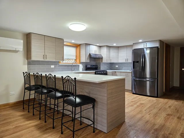 a kitchen with granite countertop a refrigerator a stove a dining table and chairs