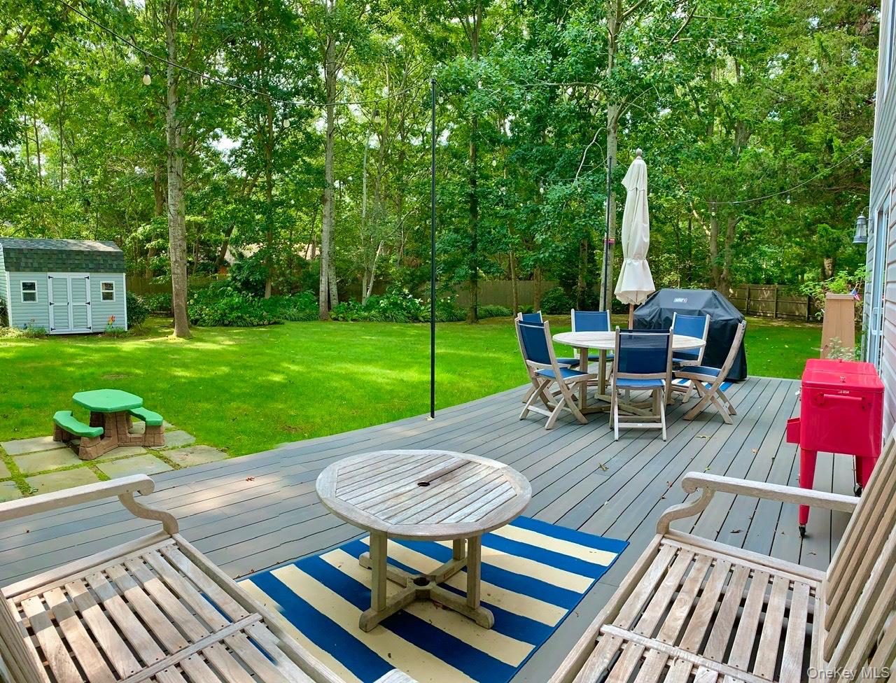 61 Kings Point Road East Hampton, NY 11937 - Photo 14 of 15 Deck featuring outdoor dining area, a shed, and view of wooded area