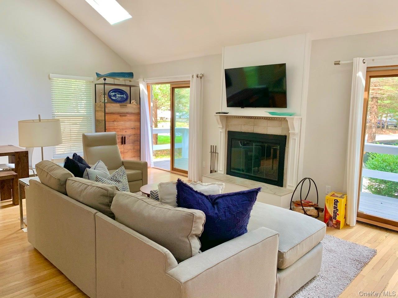 61 Kings Point Road East Hampton, NY 11937 - Photo 4 of 15 Living room with light wood-style floors, a skylight, a premium fireplace, and high vaulted ceiling