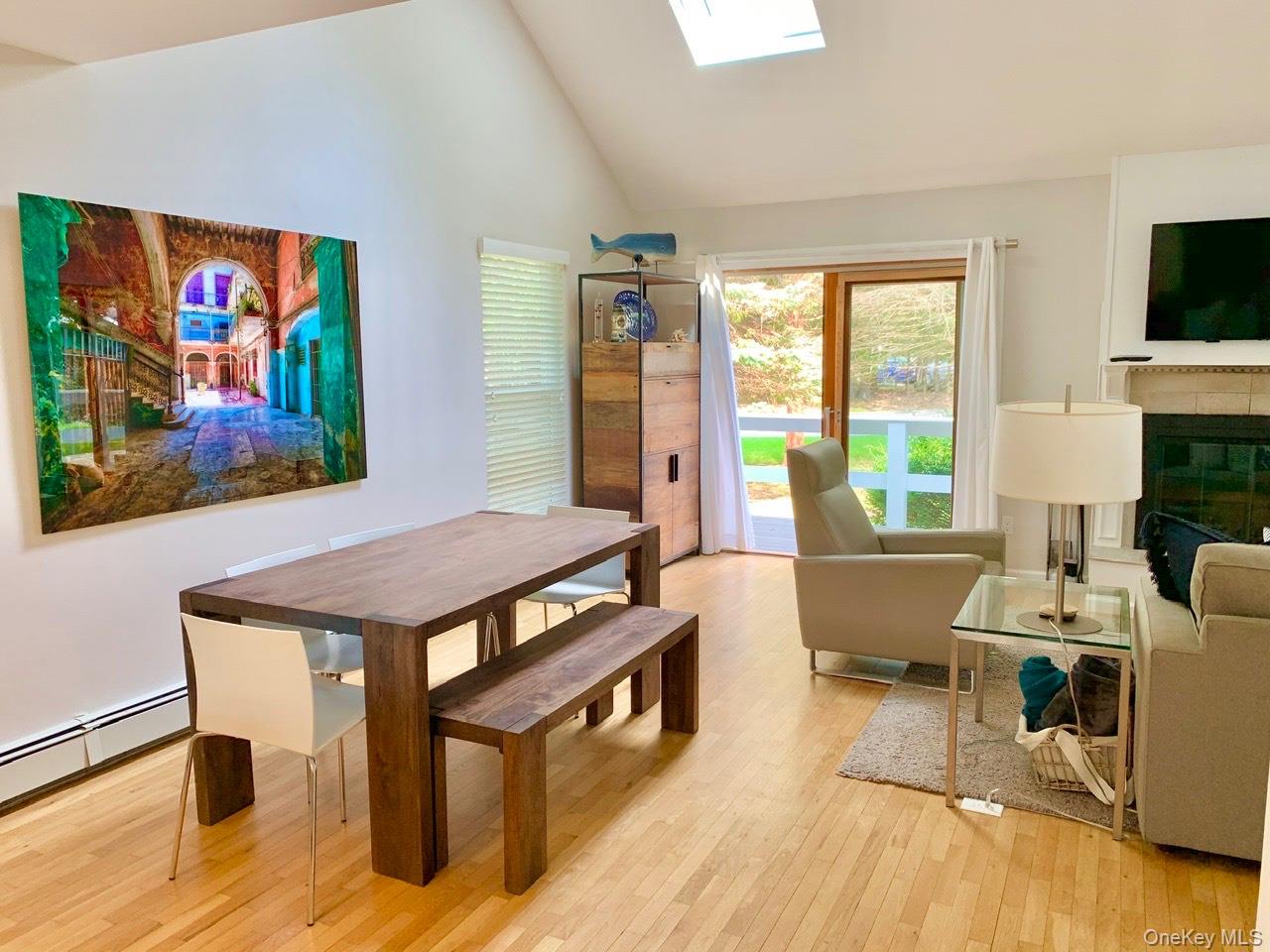 61 Kings Point Road East Hampton, NY 11937 - Photo 5 of 15 Dining space with light wood finished floors, a glass covered fireplace, a skylight, and high vaulted ceiling