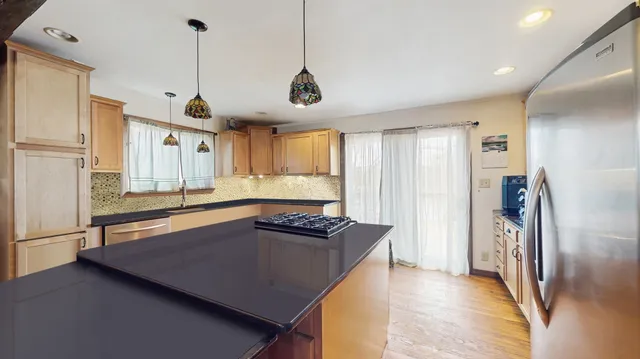 a kitchen with stainless steel appliances granite countertop a refrigerator a sink and a stove