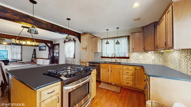 a kitchen with a stove a sink and wooden floor