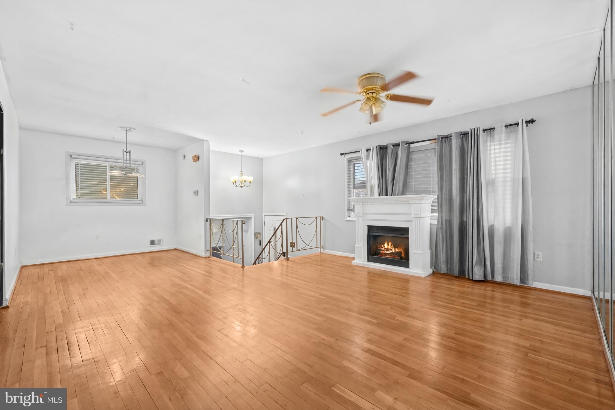 8906 Scheurer Street Lanham, MD 20706 - Photo 6 of 21 a view of a livingroom with a fireplace a chandelier fan and windows