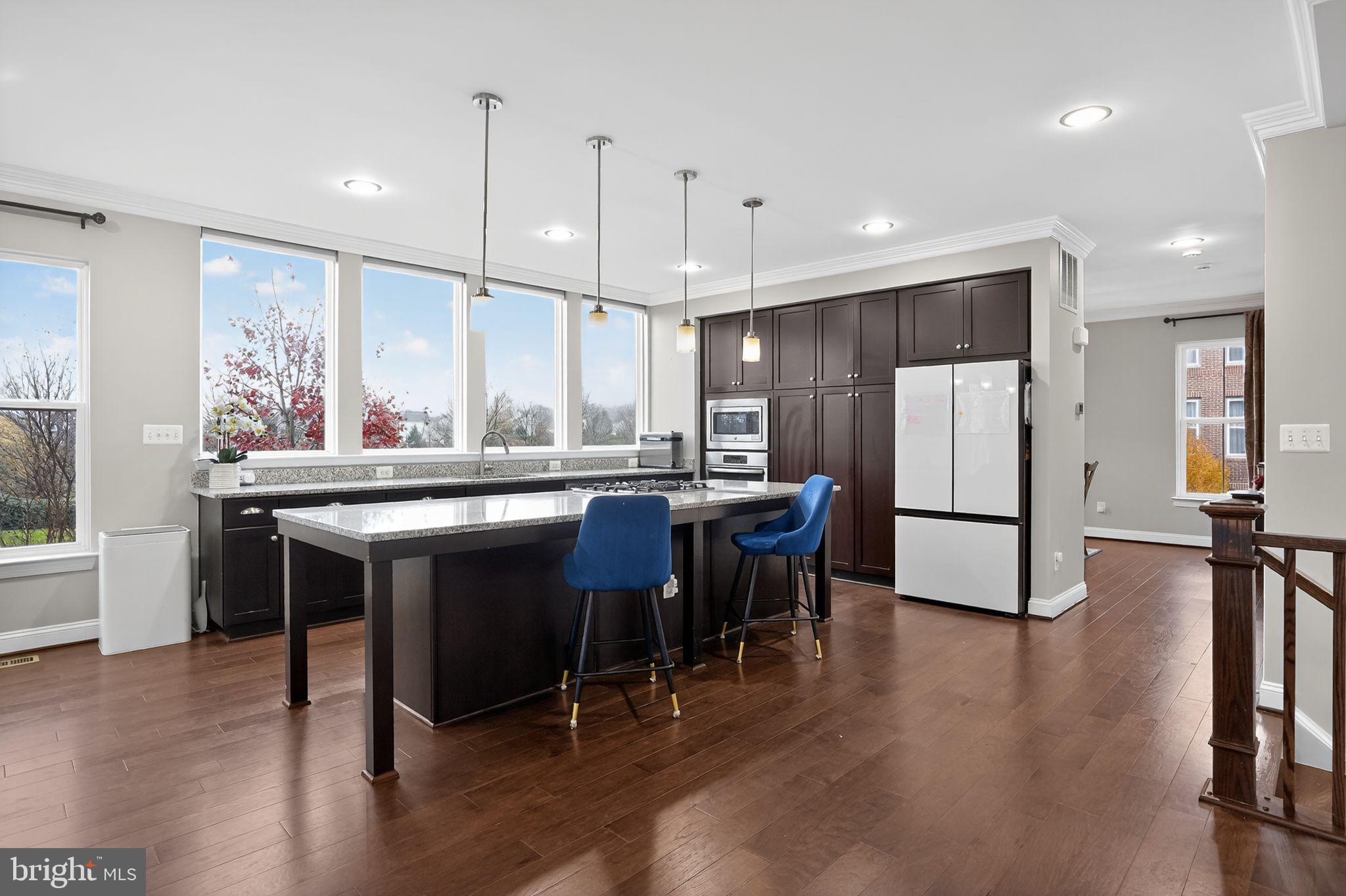 42239 Riggins Ridge Terrace Brambleton, VA 20148 - Photo 6 of 30 a kitchen with stainless steel appliances granite countertop a table chairs refrigerator and a sink