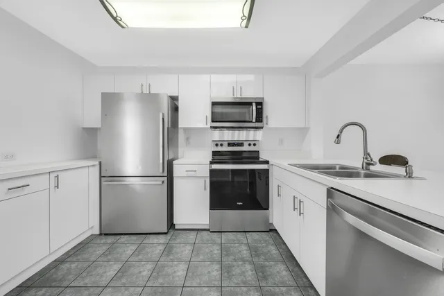 a kitchen with a refrigerator sink and white cabinets