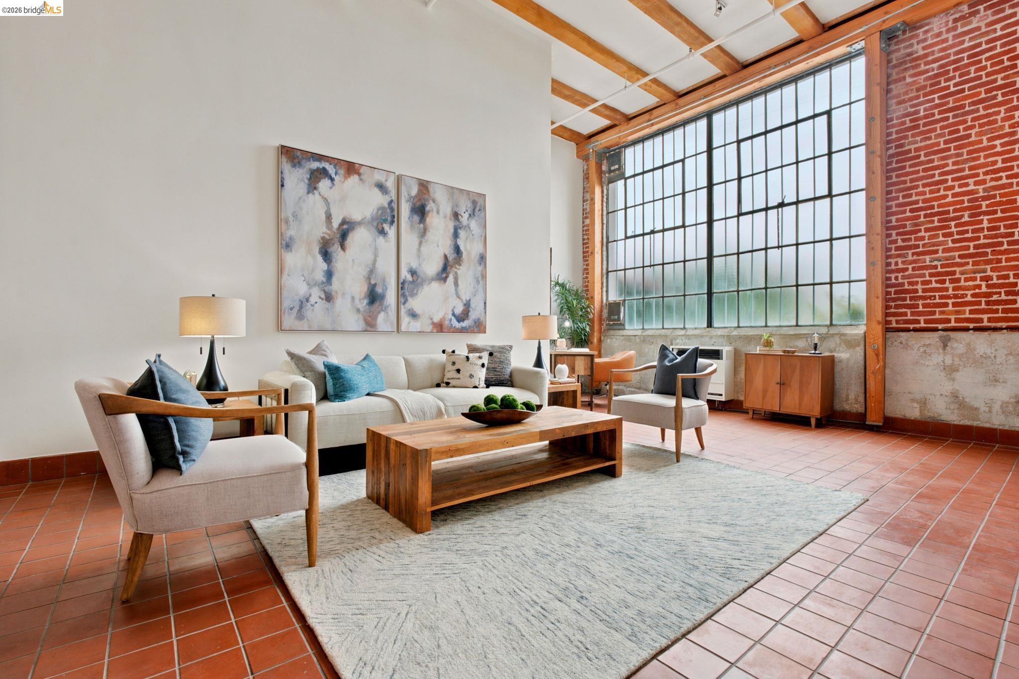 1920 Union Street, Unit 9 Oakland, CA 94607 - Photo 9 of 35 Spacious living area featuring exposed brick, high ceilings with exposed wood beams, and expansive industrial-style window panels