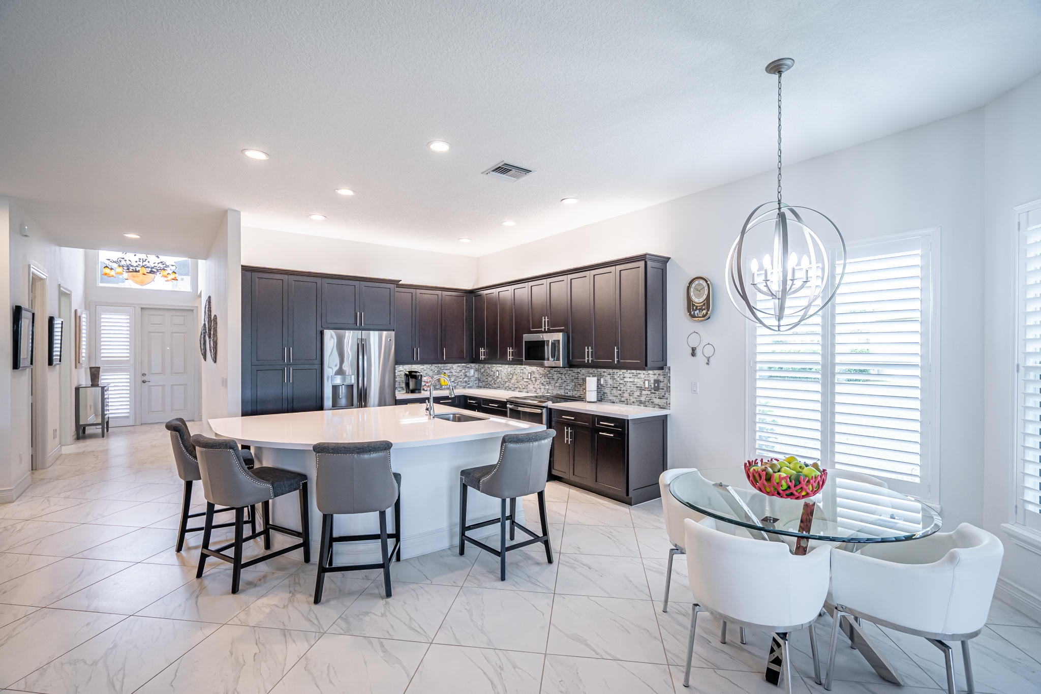 12591 Bonnington Range Drive Boynton Beach, FL 33473 - Photo 5 of 62 a kitchen with stainless steel appliances granite countertop a sink a stove a dining table and chairs