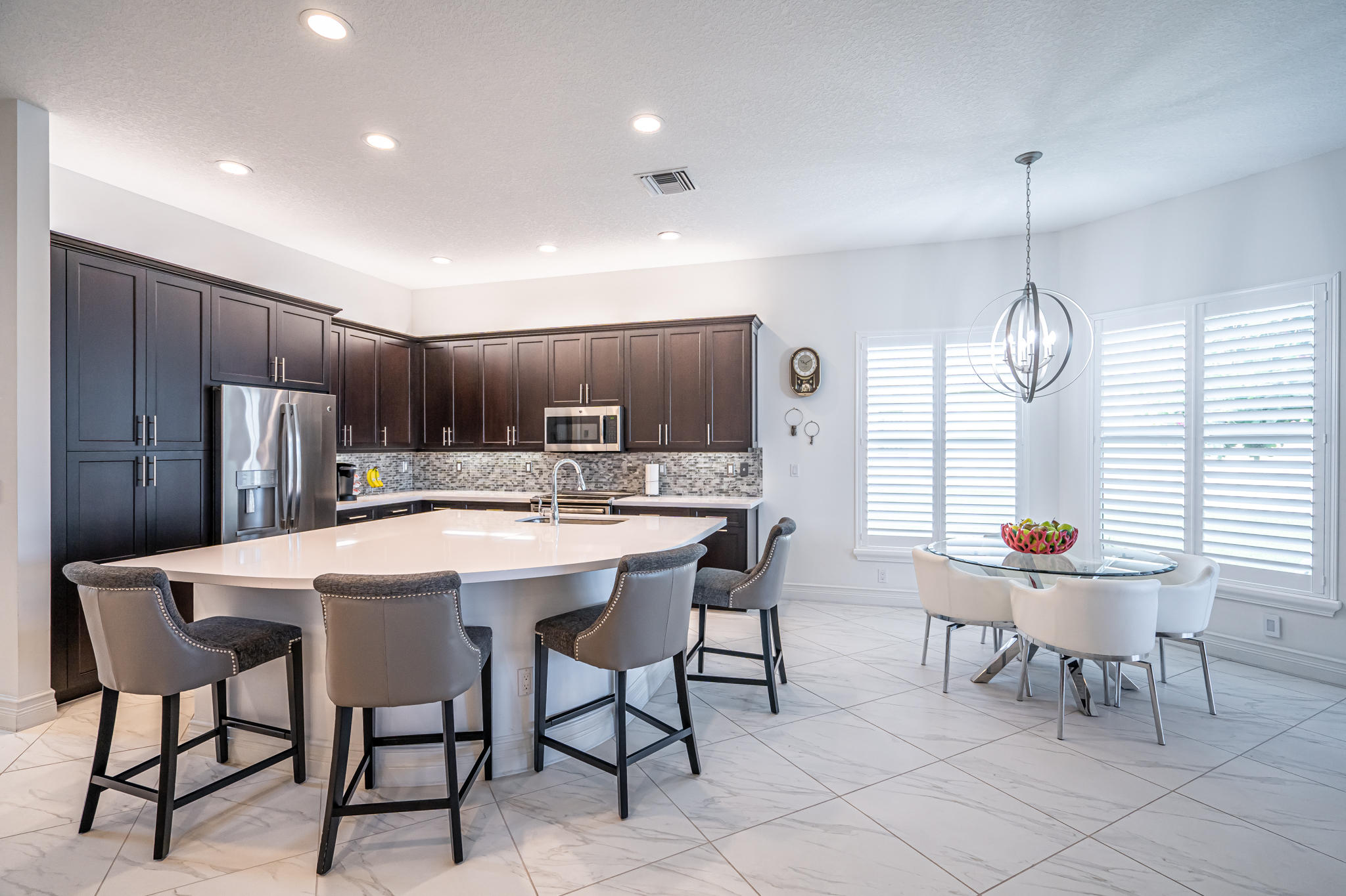 12591 Bonnington Range Drive Boynton Beach, FL 33473 - Photo 6 of 62 a kitchen with stainless steel appliances kitchen island granite countertop a dining table chairs and a refrigerator
