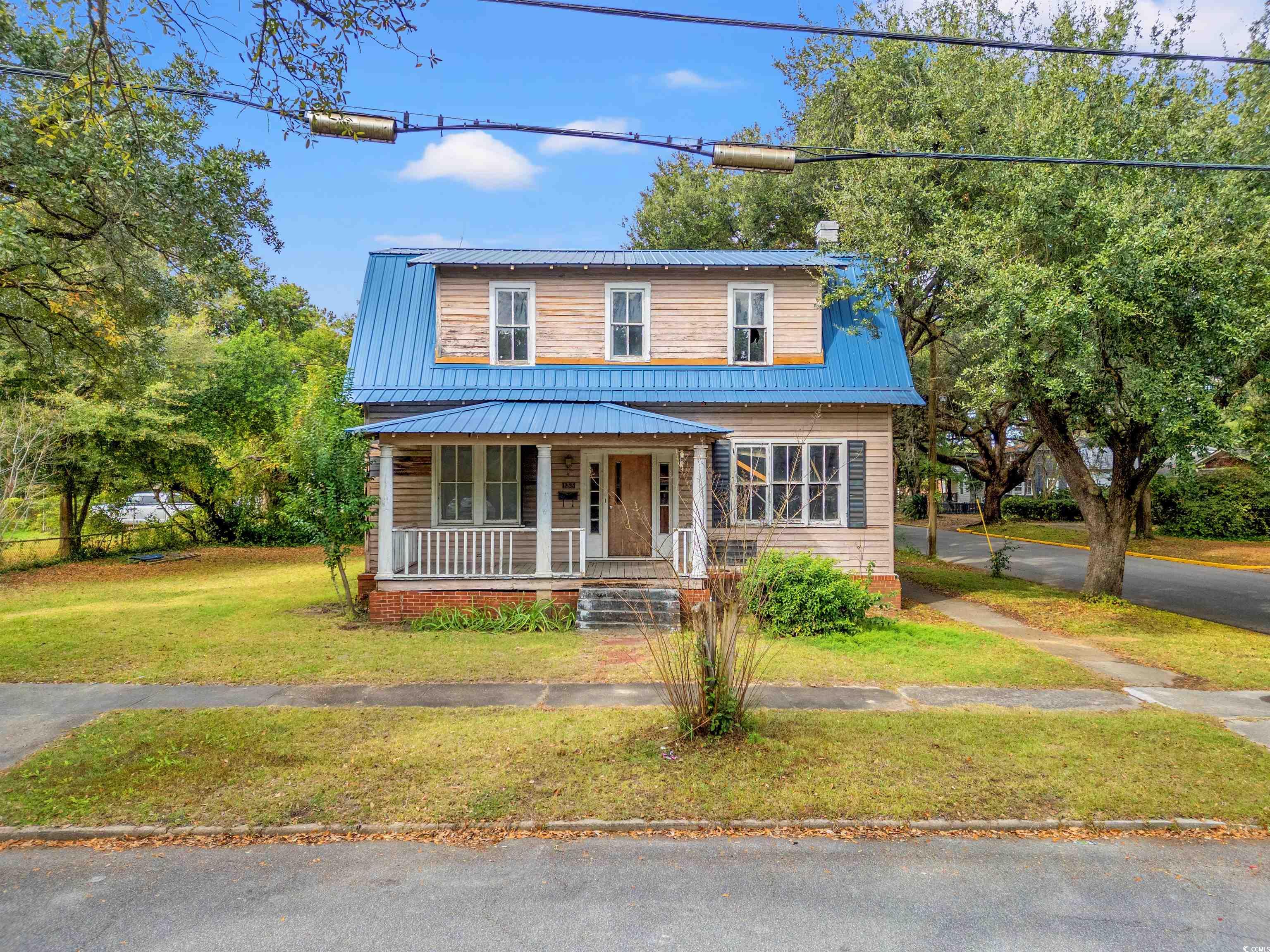 133 Wood Street Georgetown, SC 29440 - Photo 27 of 37 View of front facade featuring a front lawn, covered porch, a metal roof, and a chimney