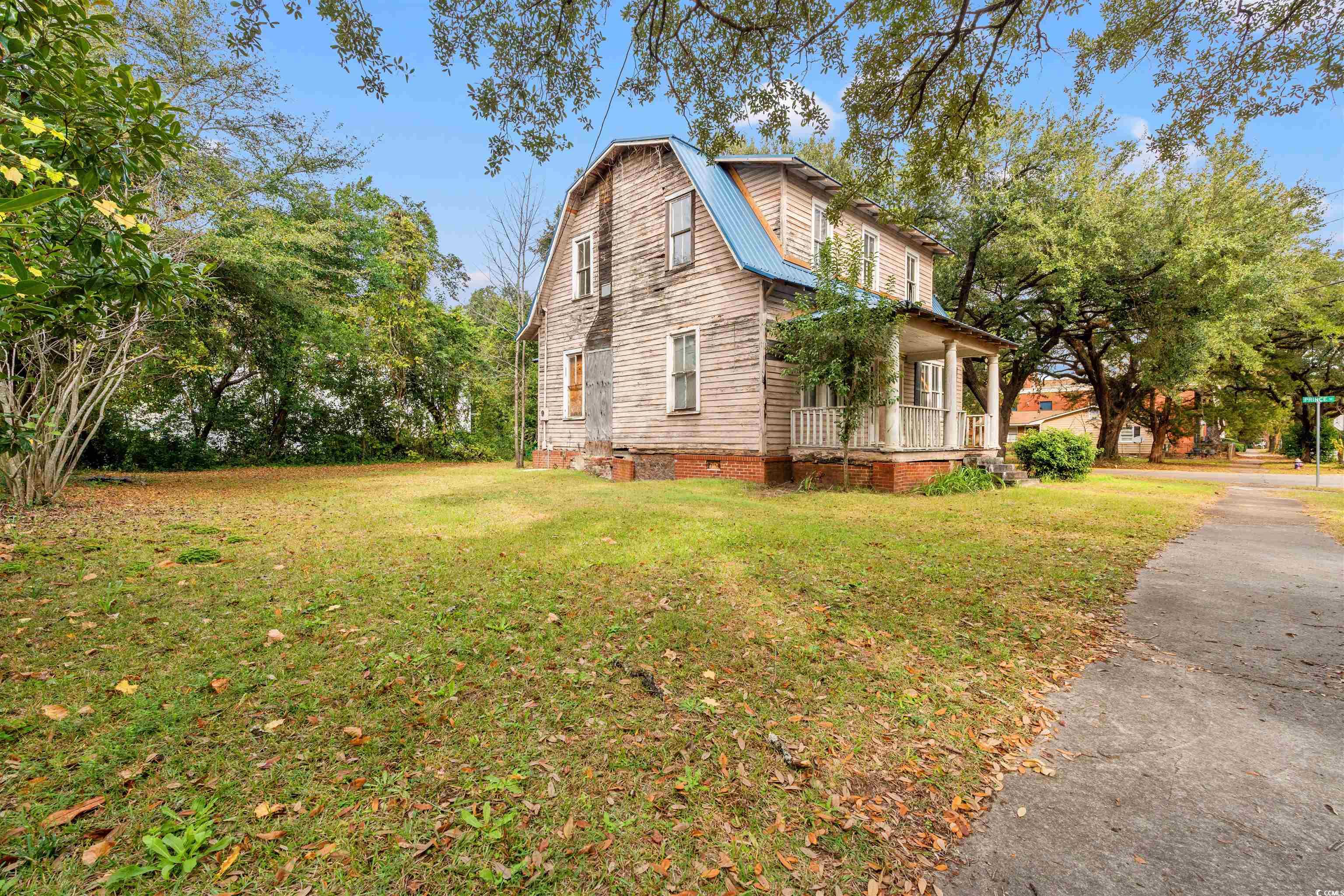 133 Wood Street Georgetown, SC 29440 - Photo 5 of 37 View of property exterior featuring a gambrel roof, a porch, a metal roof, and a lawn