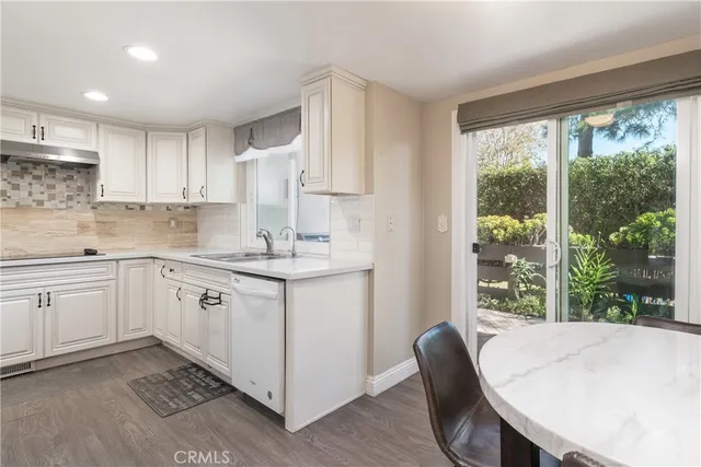 a kitchen with a white cabinets and wooden floor
