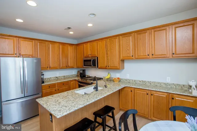 a kitchen with granite countertop wooden cabinets a refrigerator a sink a stove a dining table and chairs