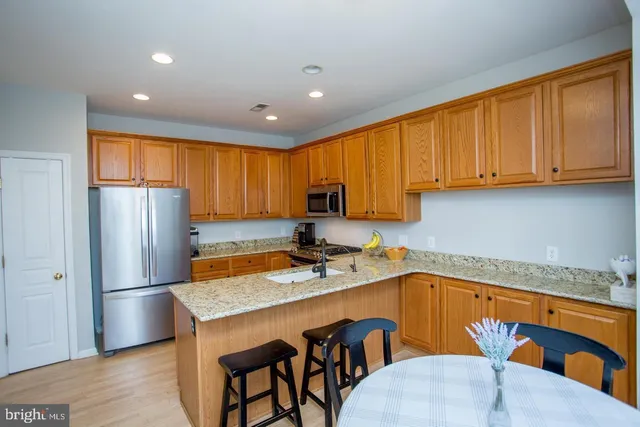 a kitchen with stainless steel appliances granite countertop a refrigerator a sink dishwasher a stove with wooden cabinets and floor