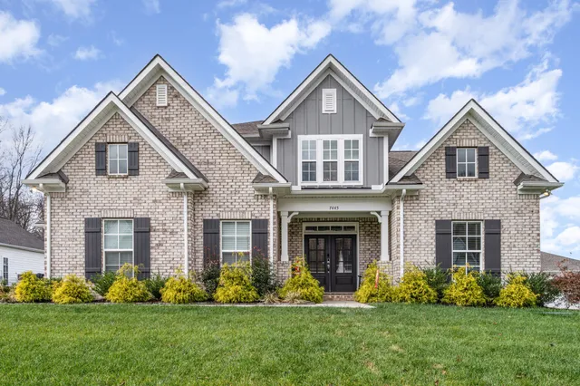 a front view of a house with a yard and green space