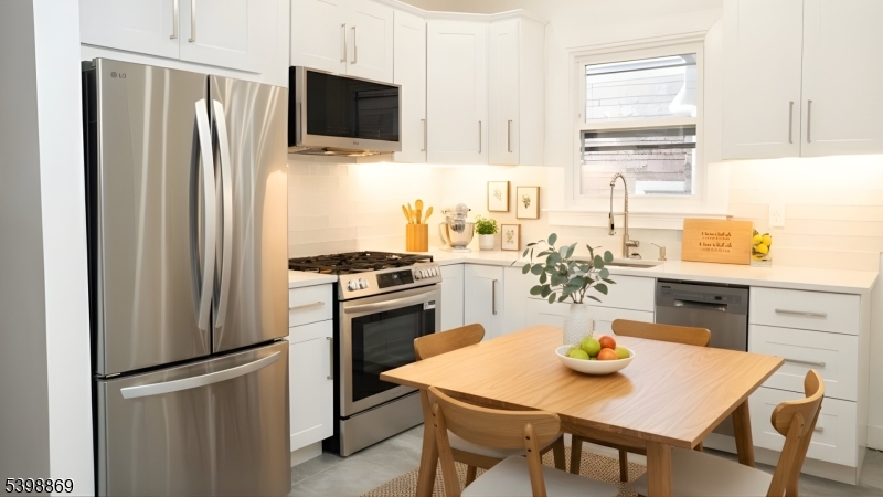 65 Poe Avenue Newark, NJ 07106 - Photo 7 of 18 a kitchen with stainless steel appliances a stove a refrigerator a dining table and chairs