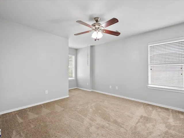 a view of an empty room with chandelier fan and a window