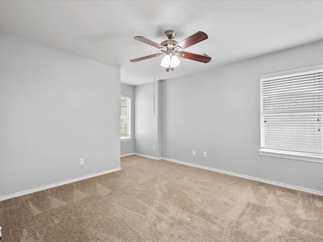 a view of an empty room with chandelier fan and a window
