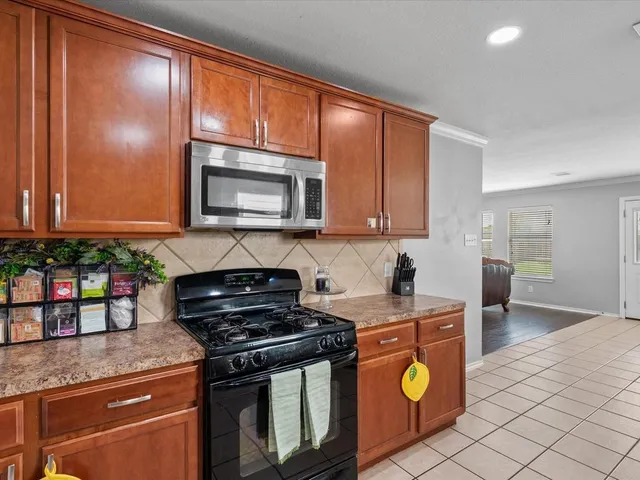 a kitchen with granite countertop a stove top oven microwave and cabinets