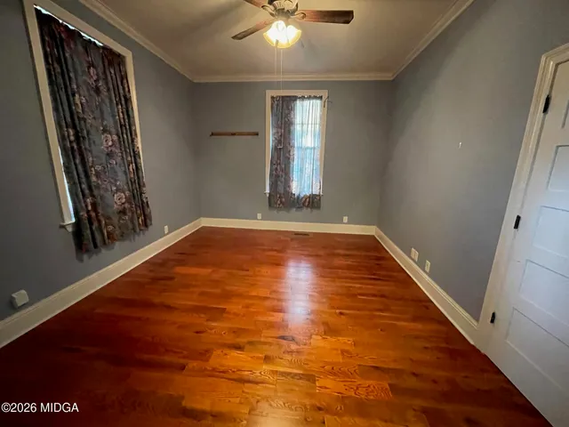 a view of an empty room with window and wooden floor